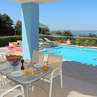 08 Nostalgia shaded dining area with pool and sea view.